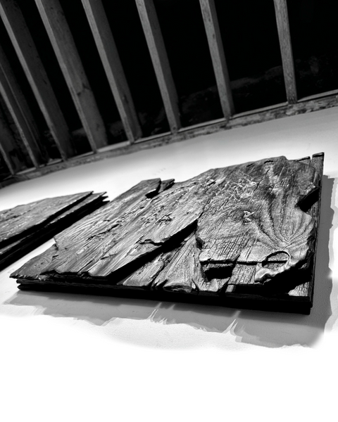 large black charred wood wall sculpture above sofa minimalist living room