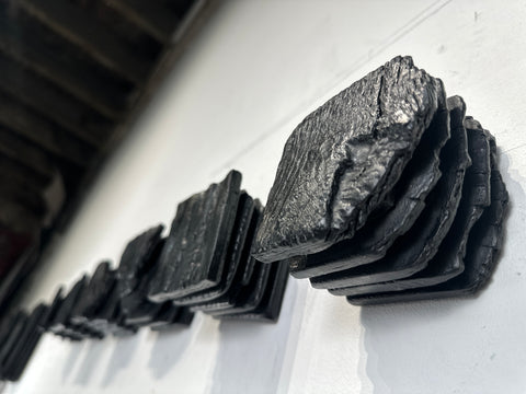 large black charred wood wall sculpture above sofa minimalist living room