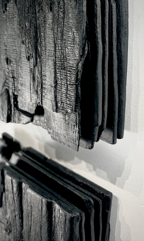 large black charred wood wall sculpture above sofa minimalist living room