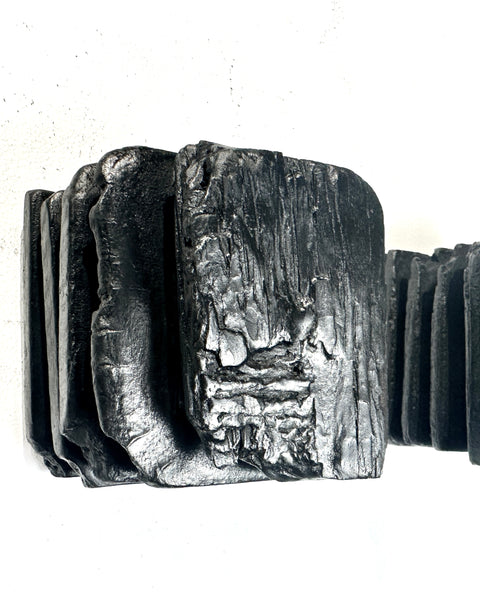 large black charred wood wall sculpture above sofa minimalist living room