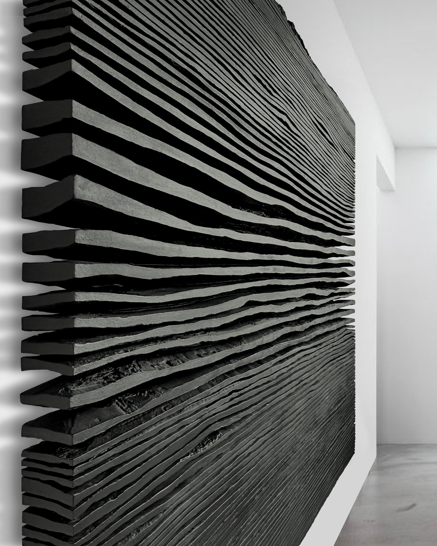 Modern interior with a black radiator against a white wall, framed pictures on the floor, and ceiling lights.