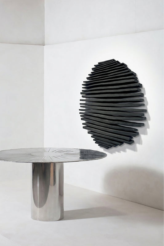 Black rod-textured wall sculpture above a round pedestal table in a pale interior
