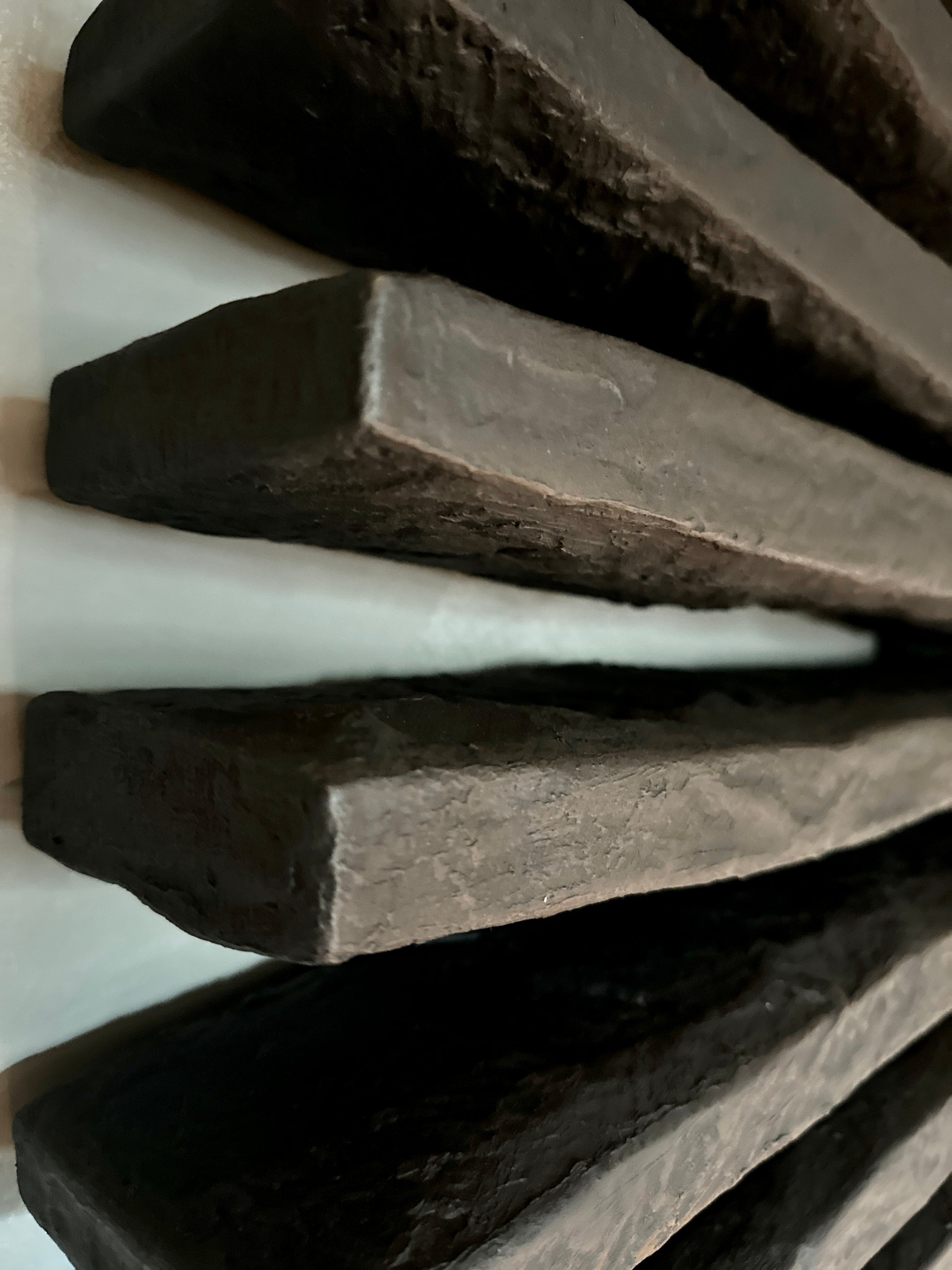 Close-up of dark chocolate bars with a white bar on a light background