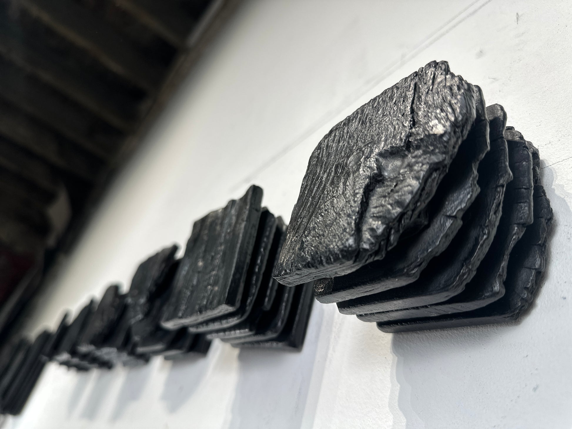 large black charred wood wall sculpture above sofa minimalist living room