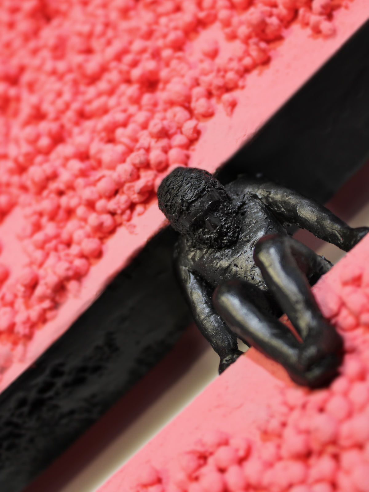 CHOICE — detail of the black figure against granular coral red surface