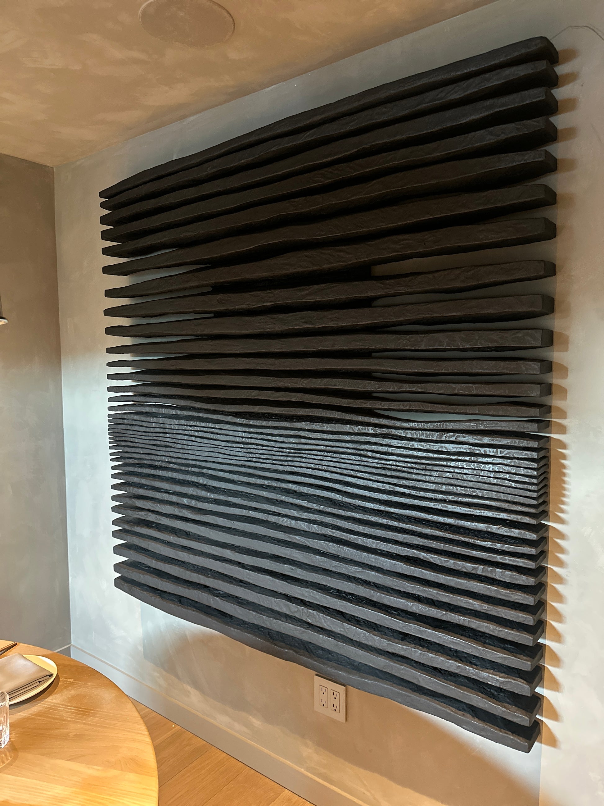 Wall-mounted acoustic panel with a slatted design in a room setting.