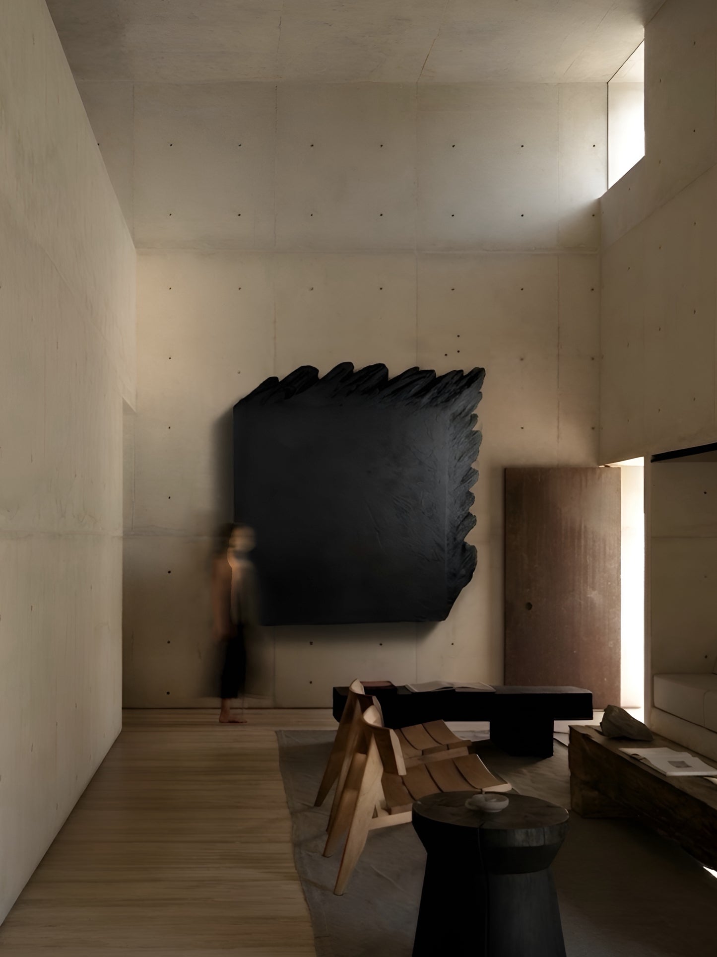 Modern interior with a large black abstract sculpture on a concrete wall.