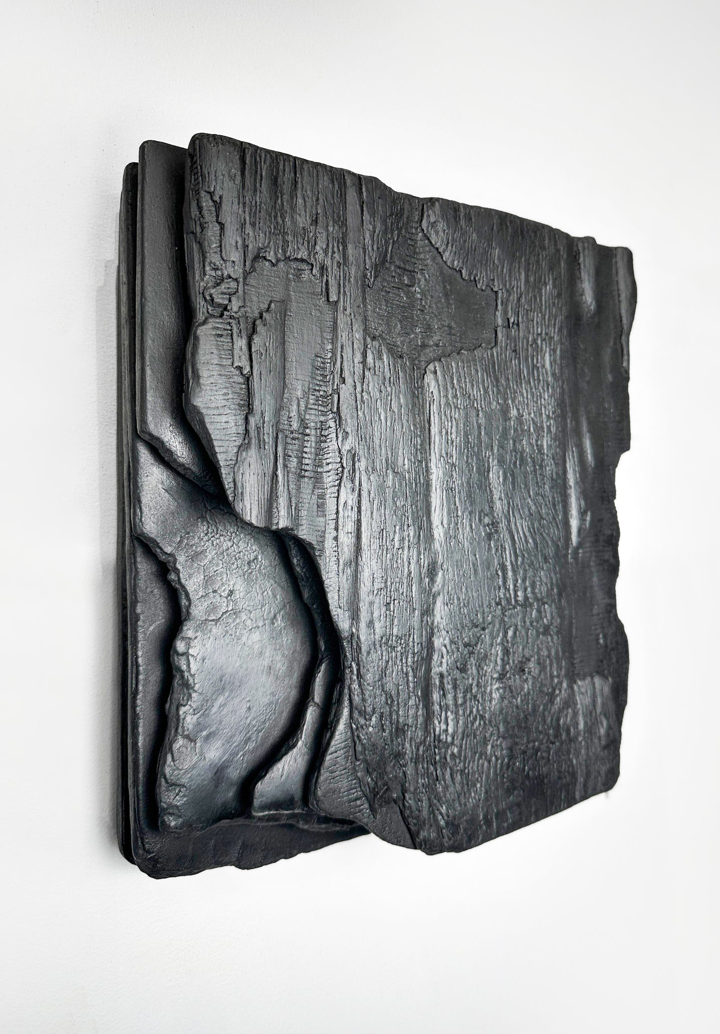 large black charred wood wall sculpture above sofa minimalist living room
