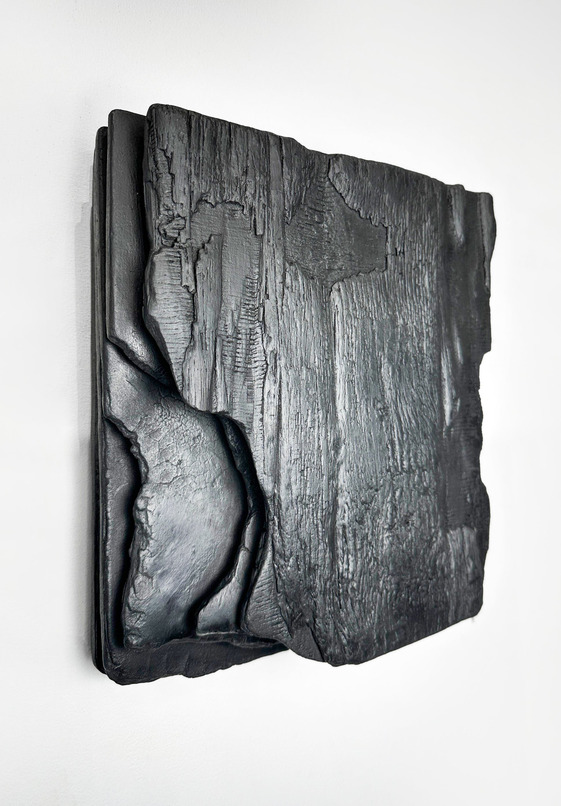 large black charred wood wall sculpture above sofa minimalist living room