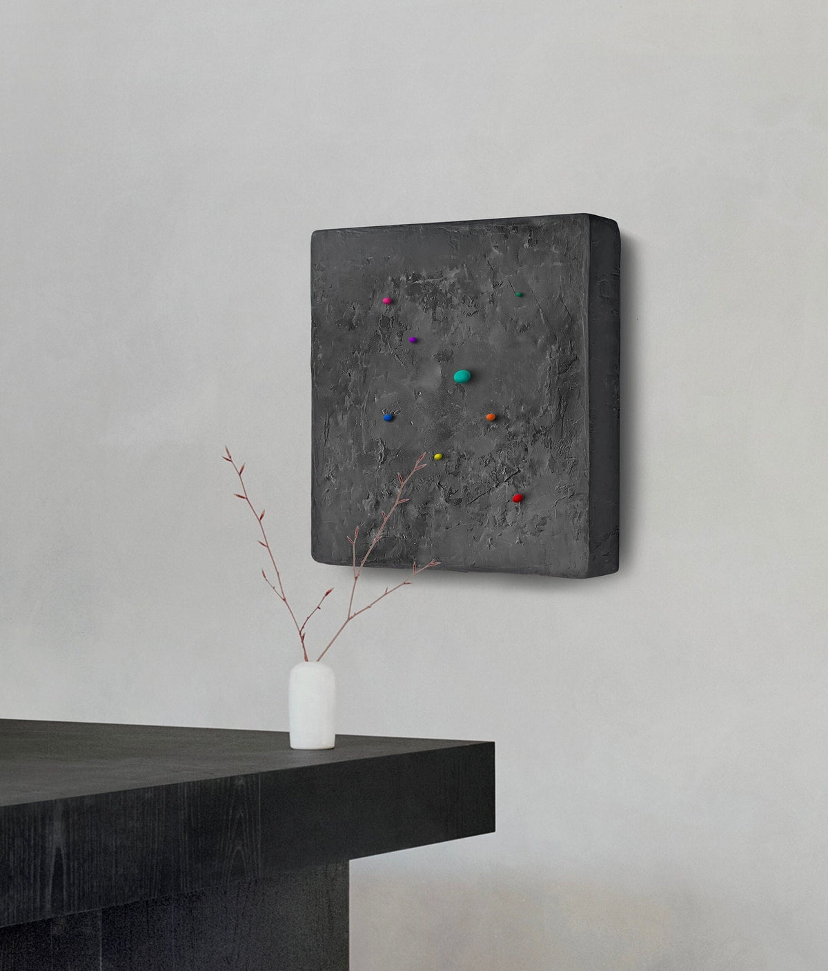 SHUN — Black base, charcoal plaster square with scattered multicolor dots above a dark table