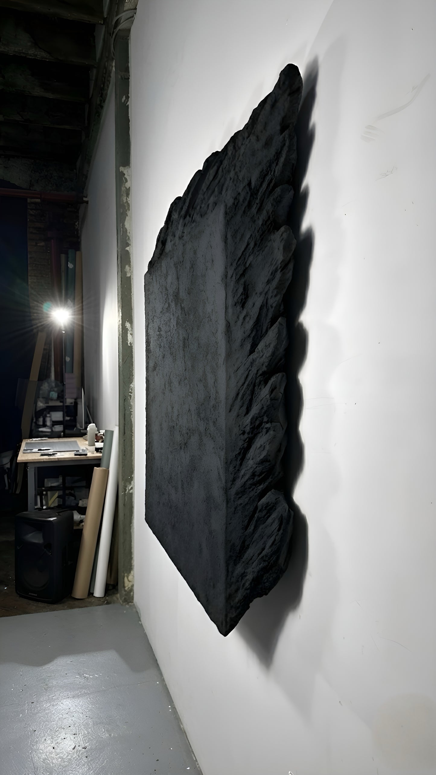 Black textured wall art on a white wall in an indoor setting