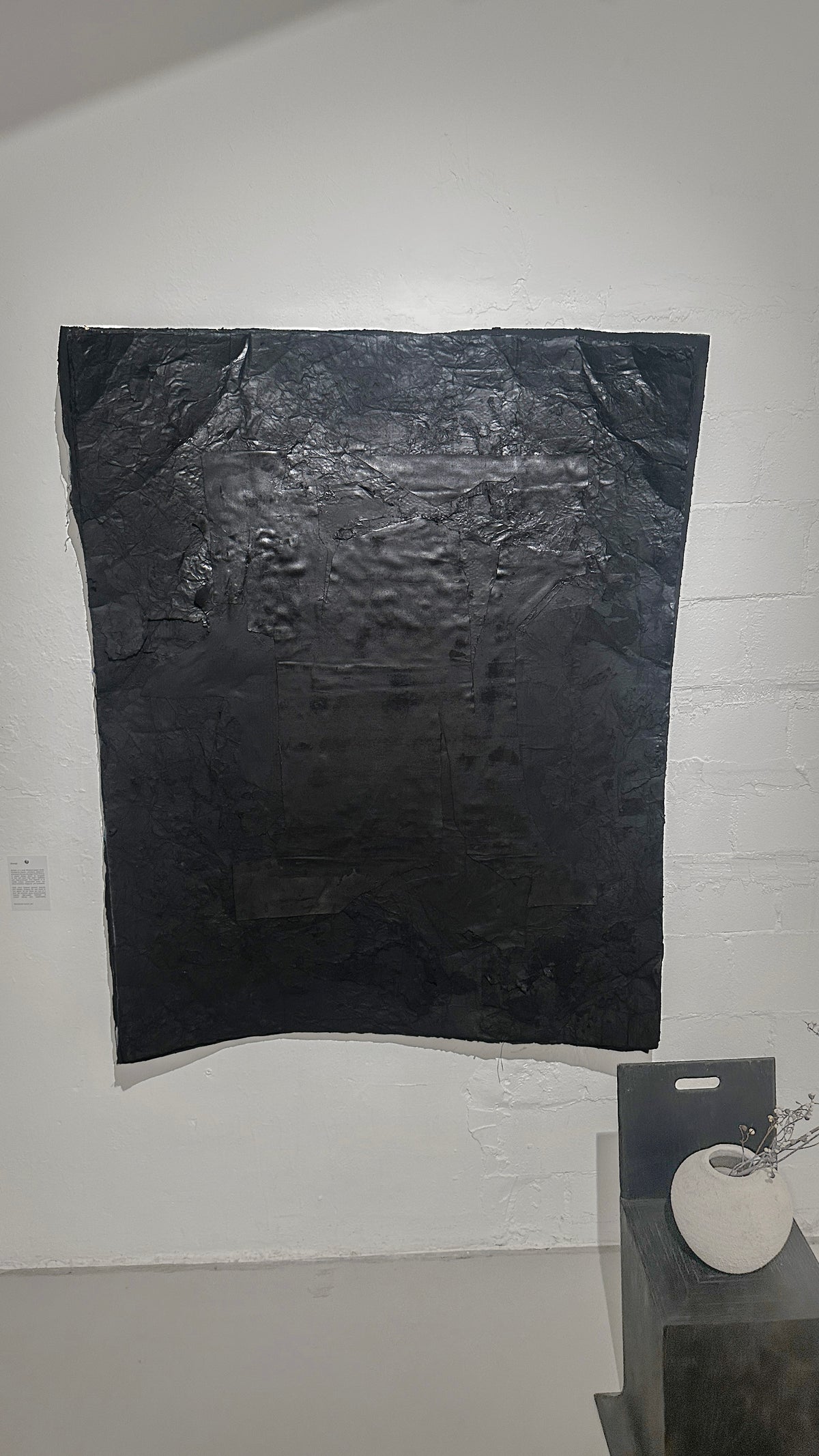 STRATA — Black, large black plaster relief on white gallery wall, frontal view