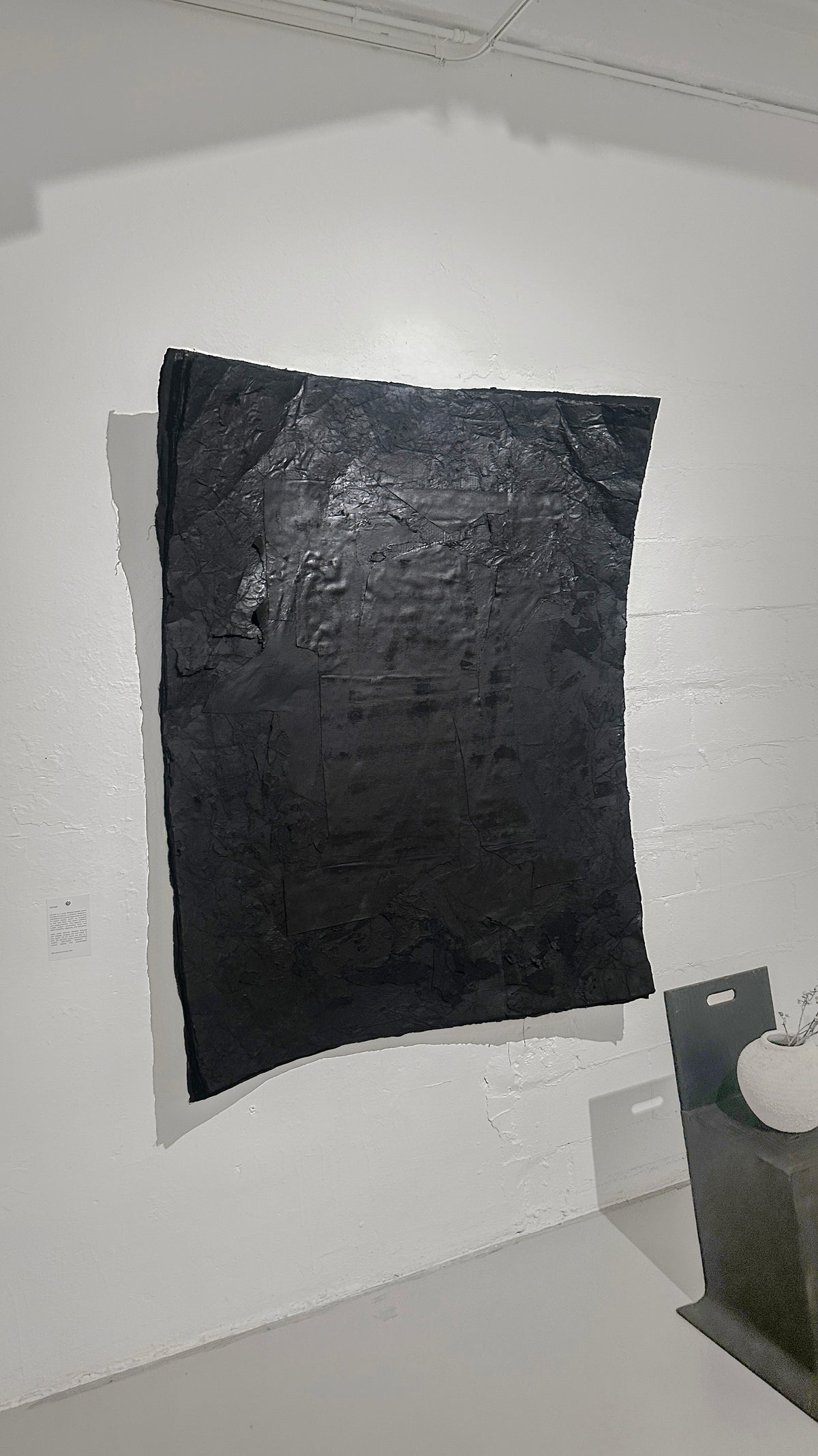 STRATA — Black, monumental black relief with layered surface, gallery installation