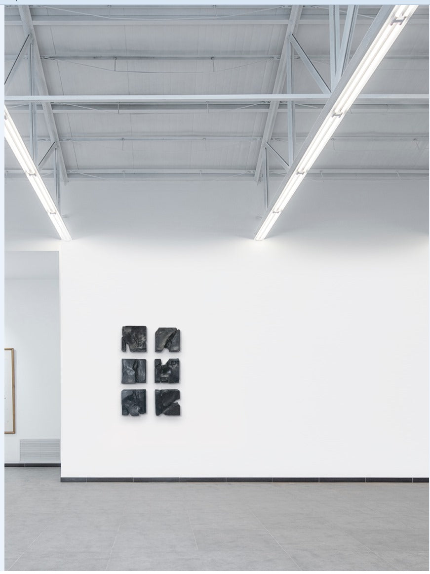 Art gallery with a white wall displaying five black abstract artworks.