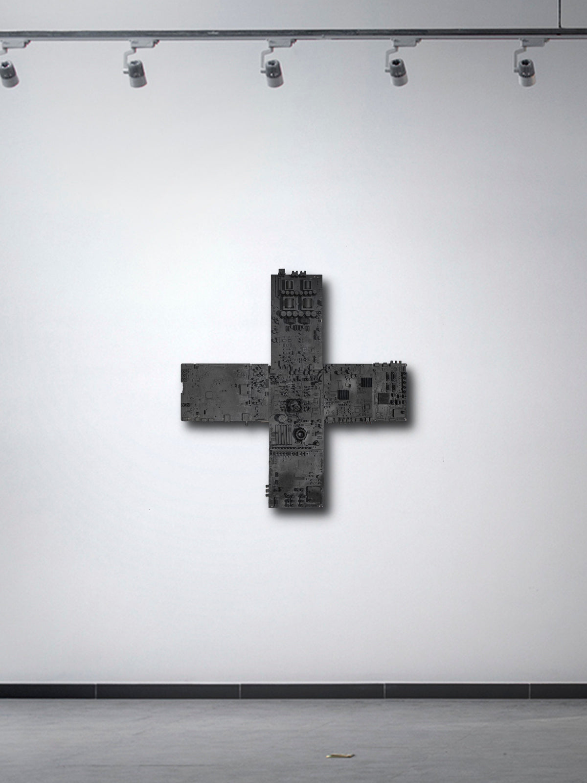 IF GOD IS IN ALL THINGS — black cross sculpture on gallery wall under track lights
