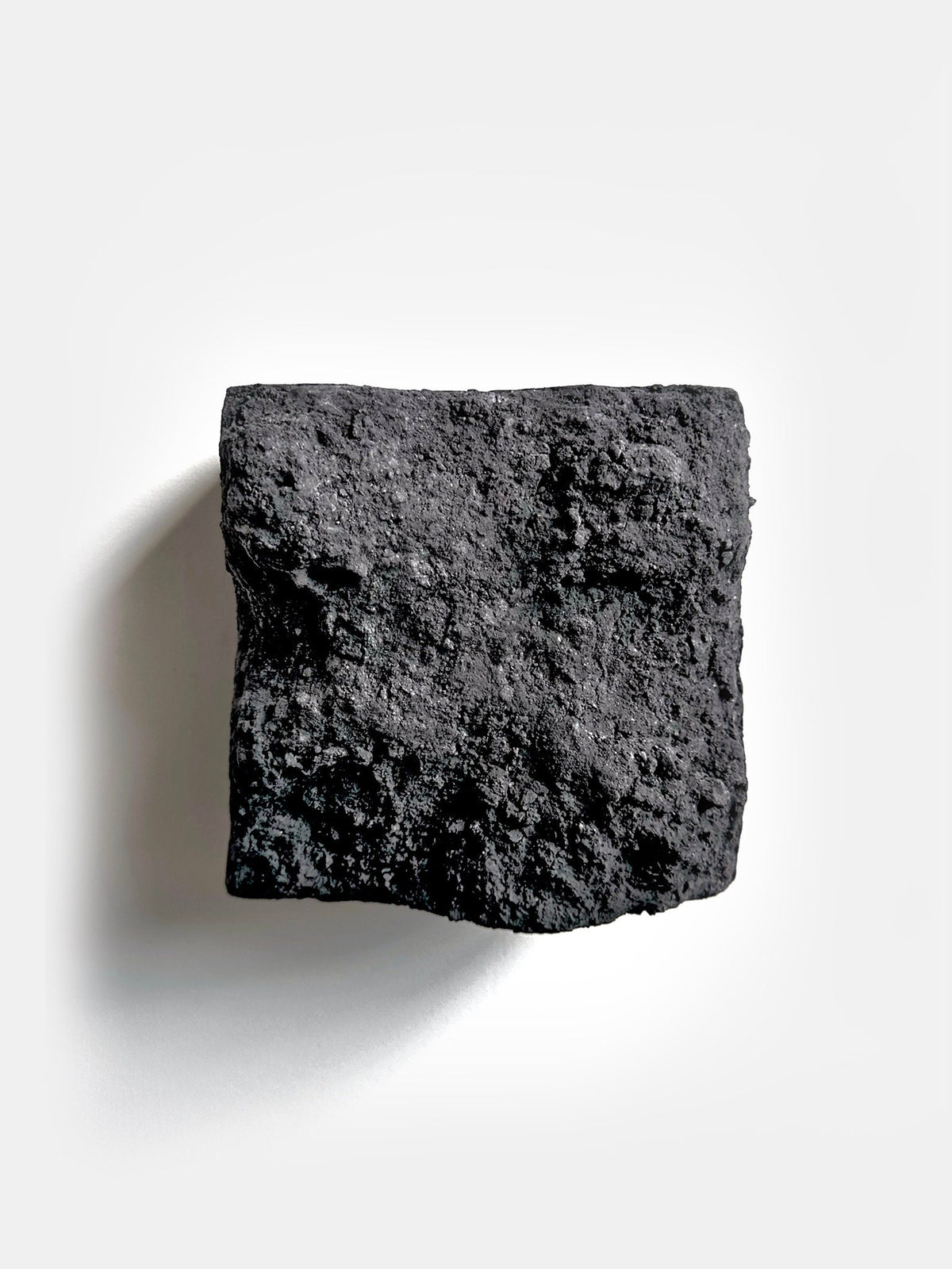 BROX — Charcoal Black, frontal view, coarse textured face of square plaster block