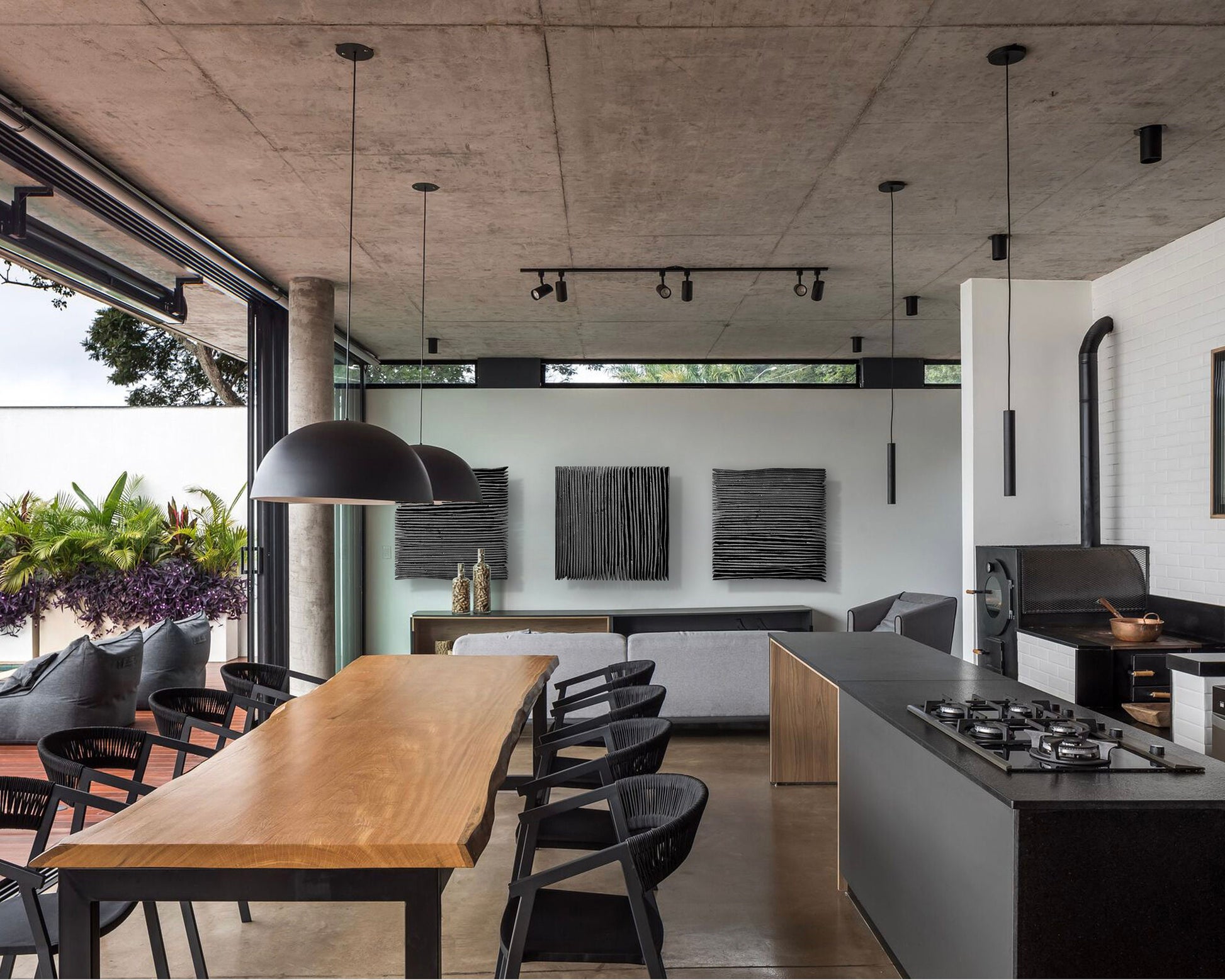 Matte black pleated plaster relief sculpture mounted above a console table in a sunlit living room with light wood floors.