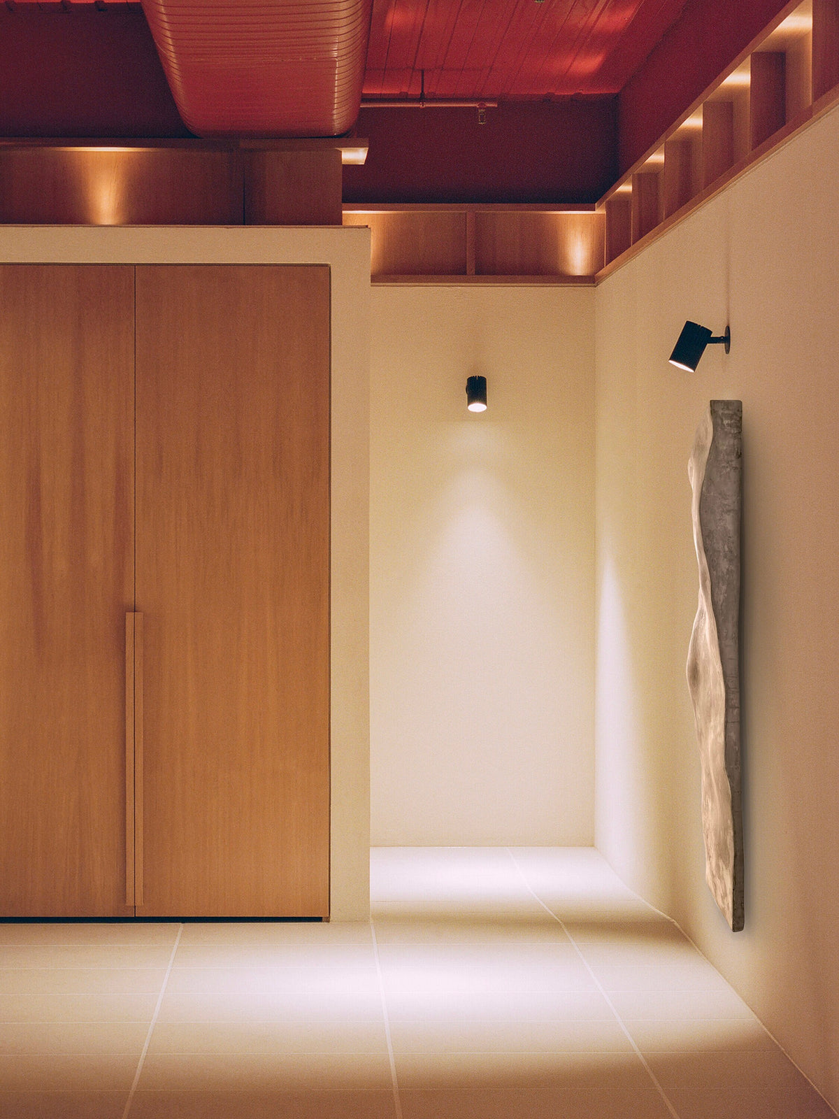 SANDSTONE — Taupe, tall sculpture in a lit hallway with wood doors