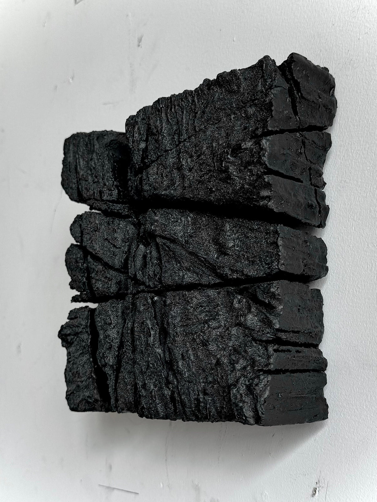 SAMURAI — Charcoal Black, side angle, stepped block edges in charcoal plaster