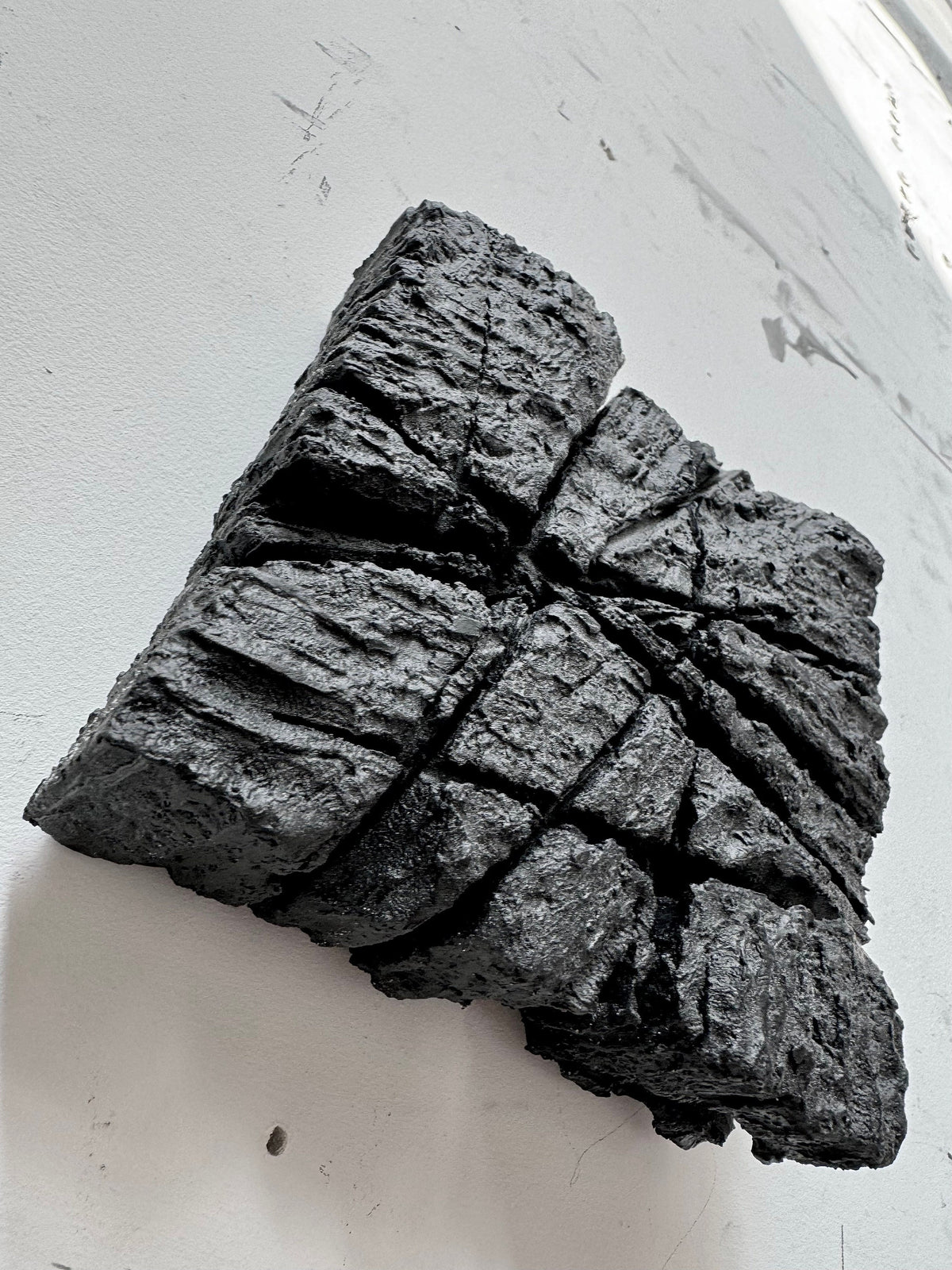 SAMURAI — Charcoal Black, angled view of fractured square relief, raking light