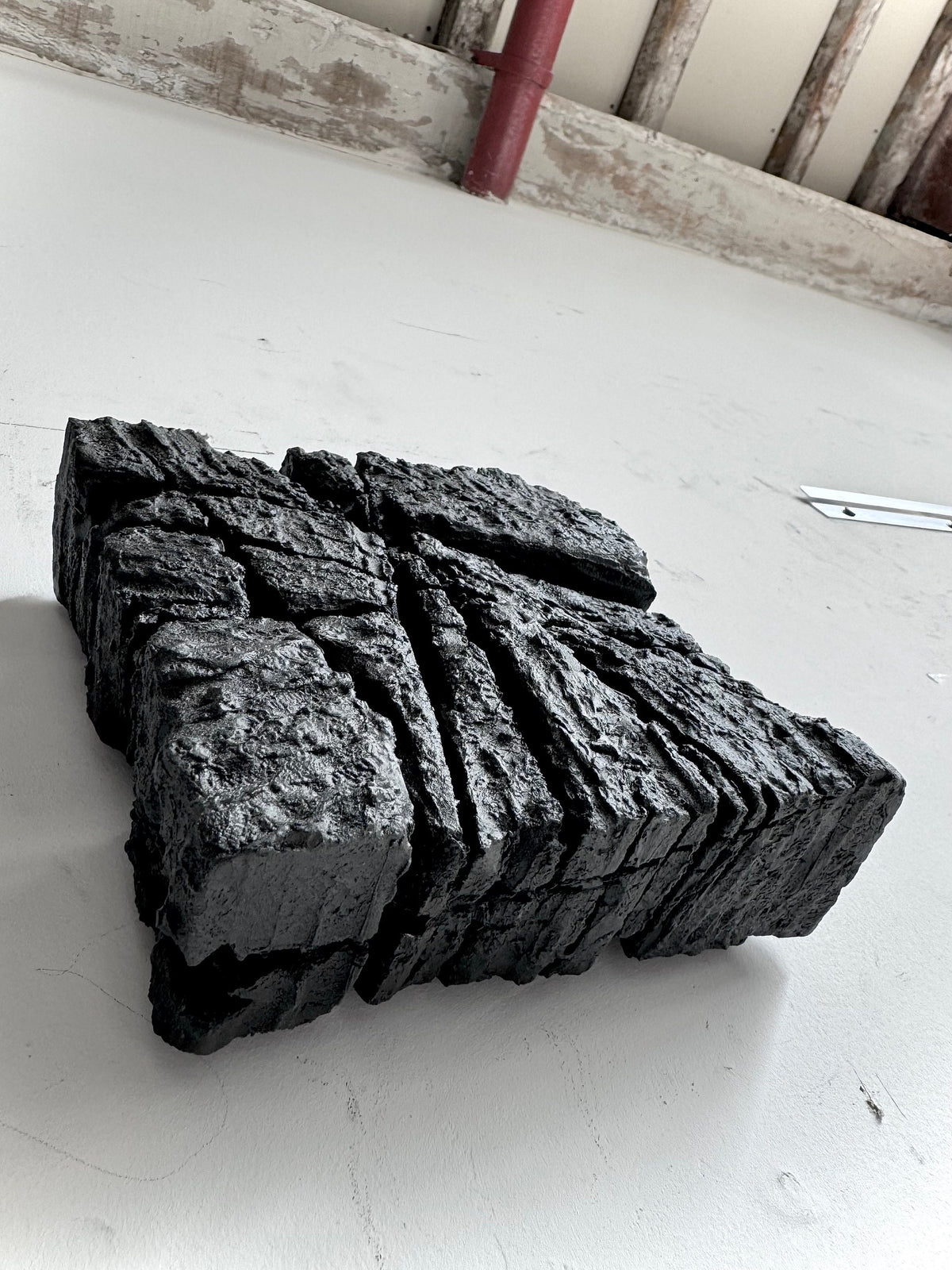 SAMURAI — Charcoal Black, overhead angle in studio, fractured square relief
