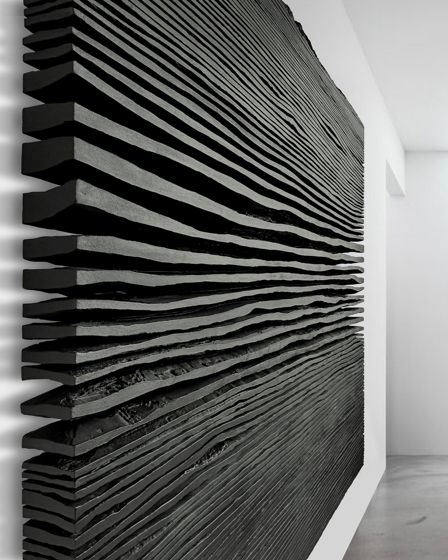 Matte black pleated plaster relief sculpture mounted above a console table in a sunlit living room with light wood floors.